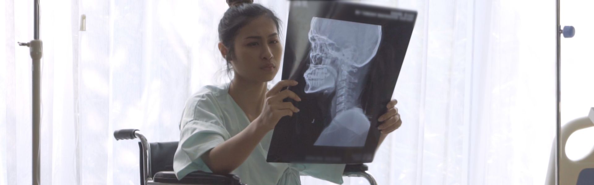 injury victim in wheelchair looking at scans of her head and brain in need of recoveries to pay her medical bills